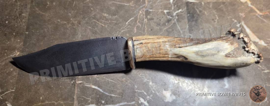 Knife with a black blade, a brass finger guard and an elk stag crown handle
